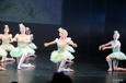 Bildet viser ballettdansere i grønne tutu kjoler på scenen. D er tekopper i Alice in Wonderland og har små te kopper på hodet. 