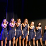 BIlder viser 8 jenter der synger til en konsert.